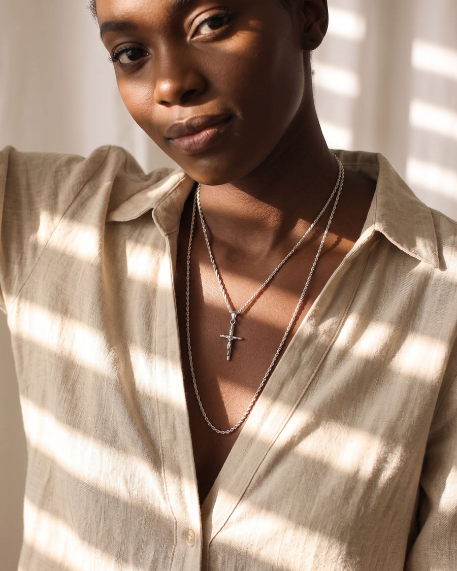 Model Image - Rhodium Pray Cross necklace layered with a delicate chain and cross pendant at the neckline worn on model