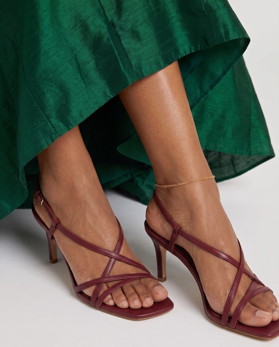 Model Image - dainty 18k Gold cable chain anklet styled at the ankle with strappy heels and a green dress worn on model