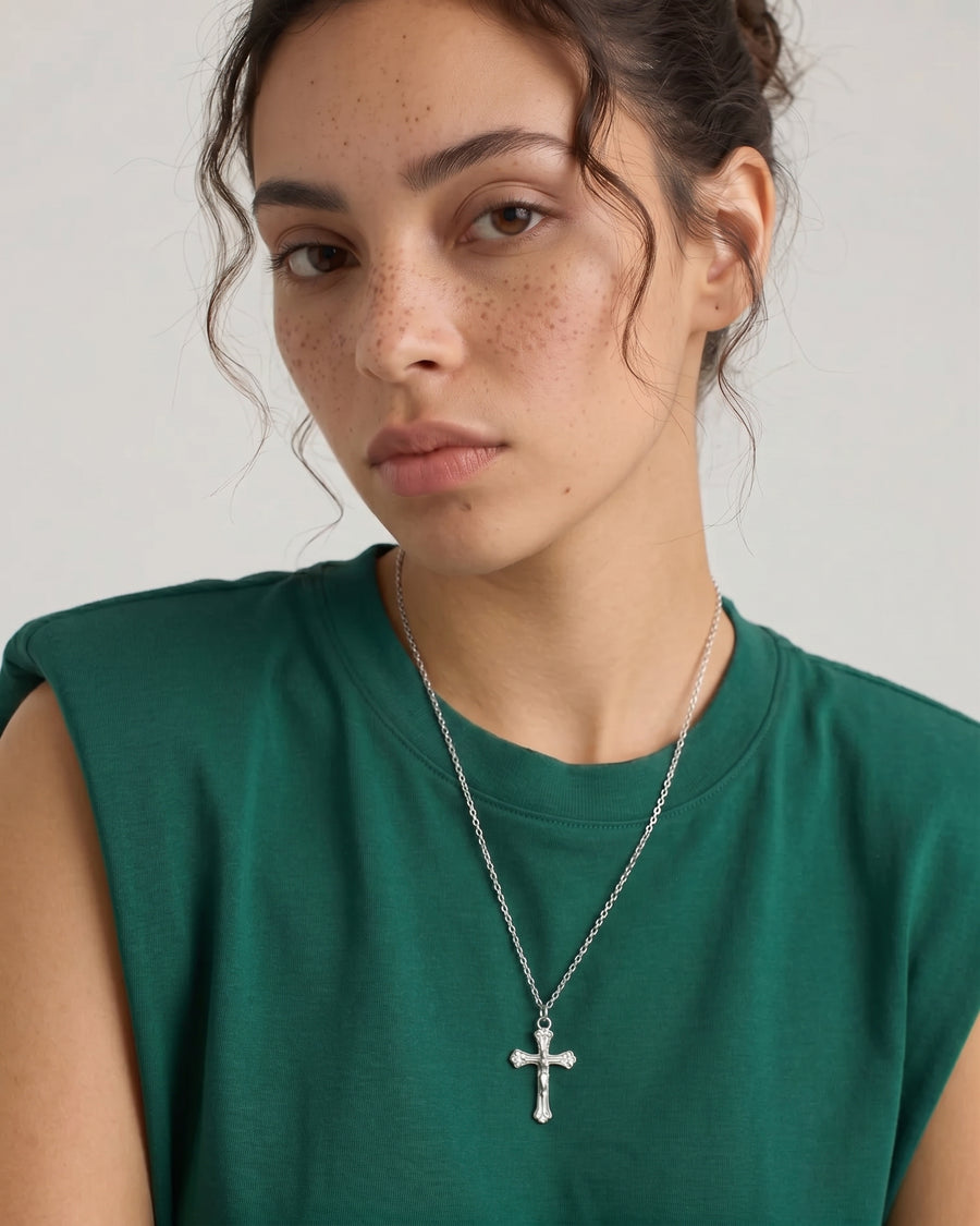 Model Image - Rhodium dainty cross necklace on a chain styled over a green top worn on model