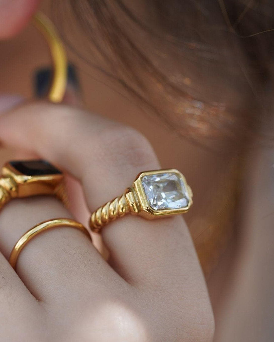 Style Image - Twisted signet ring with diamond on hand, styled with other gold-toned rings.
