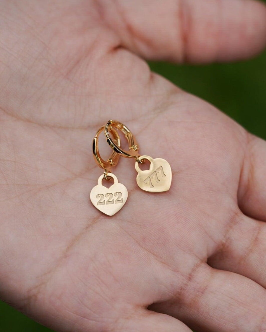 Detail Image - Gold plated heart hoop earrings with 222 angel number pendants held in an open palm