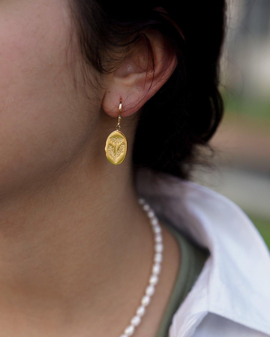 Model Image - Oval birth flower earring with a small hoop and oval floral pendant worn on model