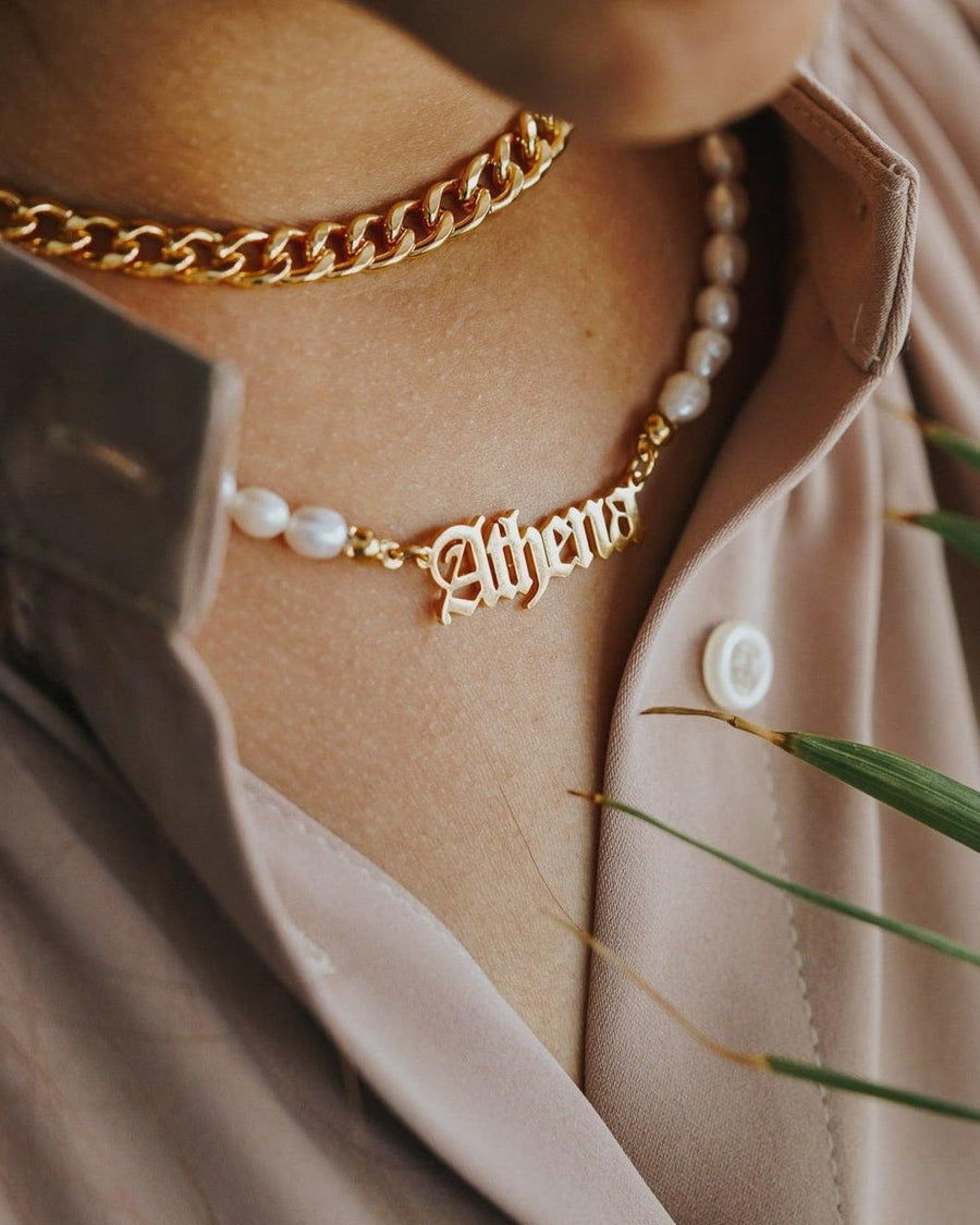 Model Image - Old English pearl name necklace layered with a gold-tone chain at the neckline worn on model