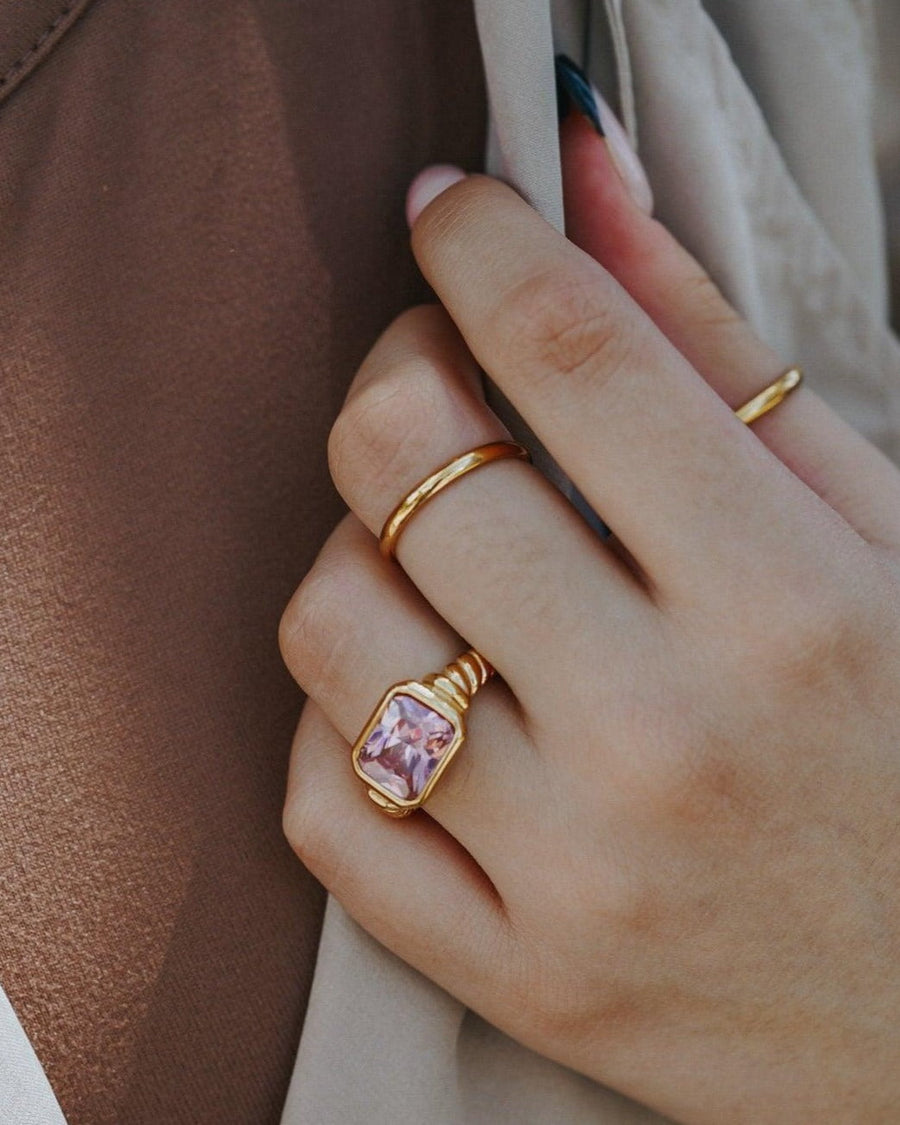 Style Image - Twisted Signet Ring in Pink with twisted band and center pink gemstone worn on hand with other rings