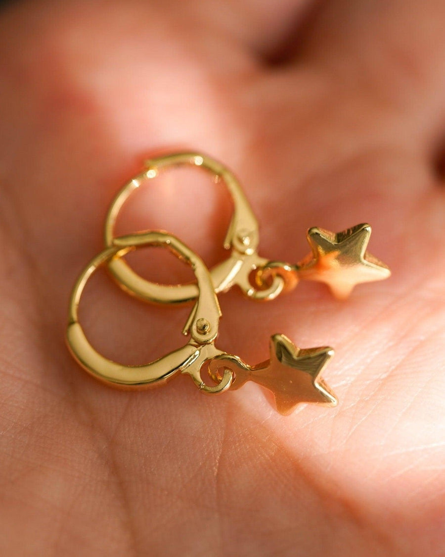 Detail Image - Star earrings with small star charms and rounded hoops held in a hand