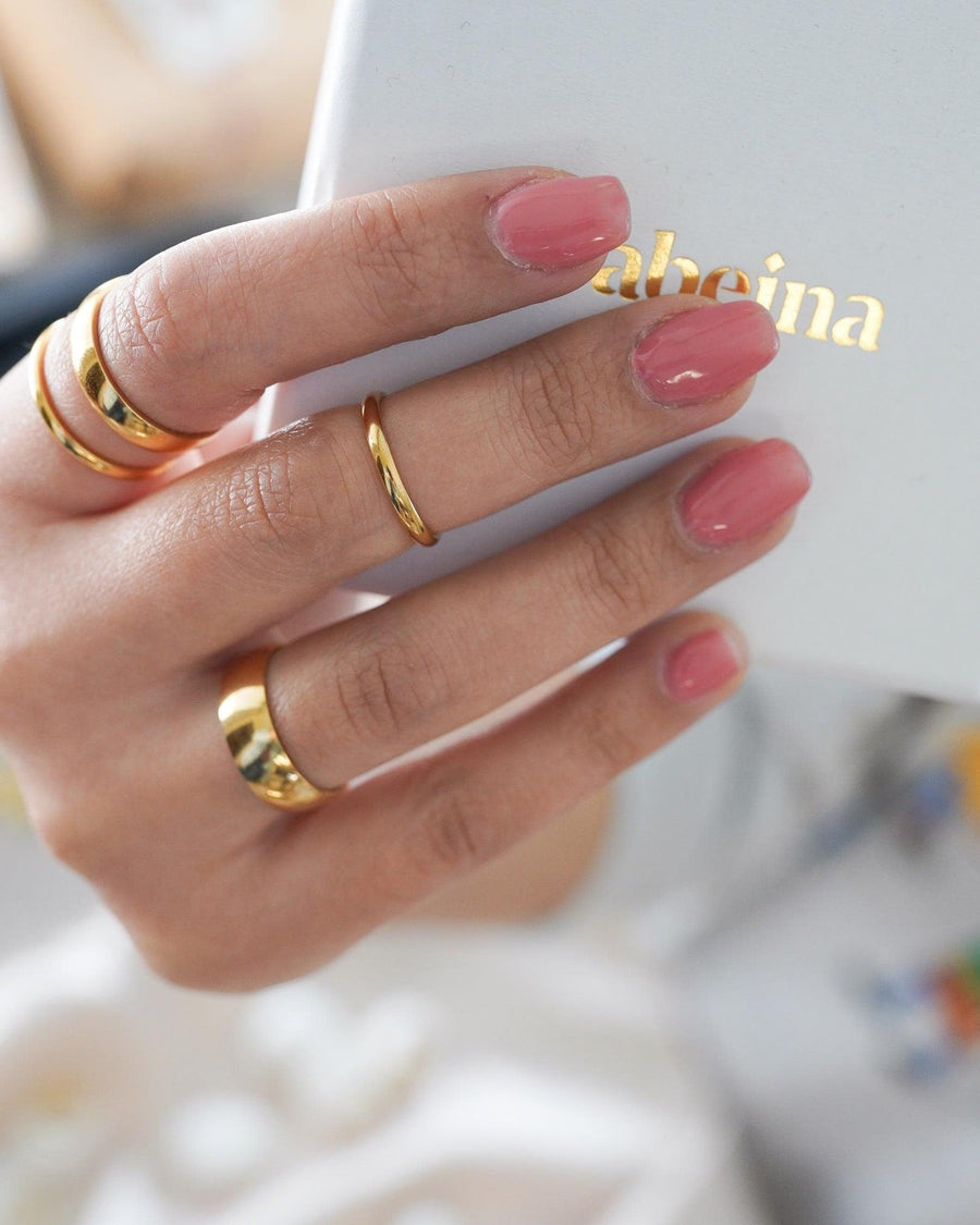 Model Image - 2mm gold plated band ring styled with other gold rings on the hand worn on model