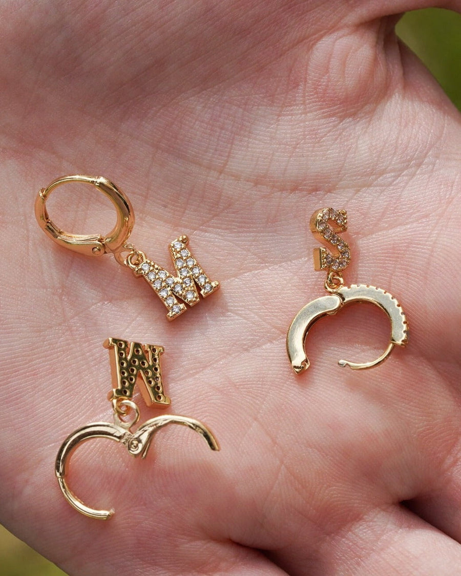 Detail Image - 14K gold plated pave initial hoop earrings with W, K, and S letter pendants displayed in hand