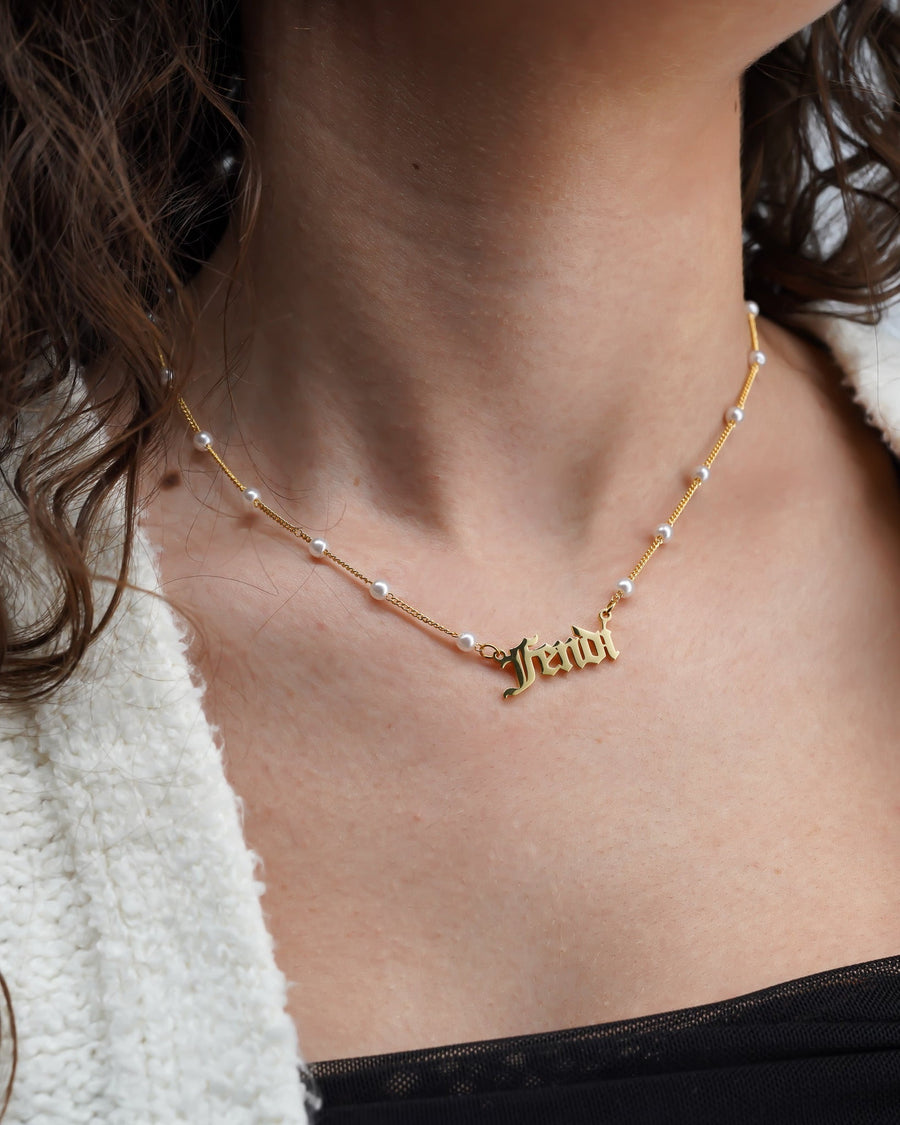 Model Image - Old English name necklace with a gold-tone script pendant on a pearl bead chain worn on model