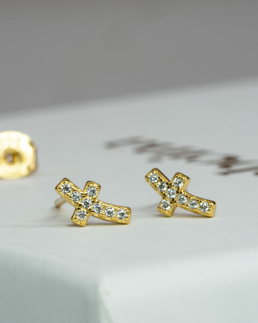 Detail Image - Tiny Cross Studs in 14k gold plated design displayed as a pair on a light surface