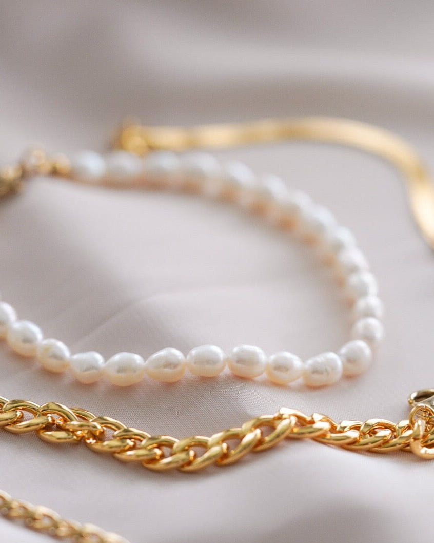 Style Image - Full Pearl Bracelet layered with gold chain bracelets on soft fabric