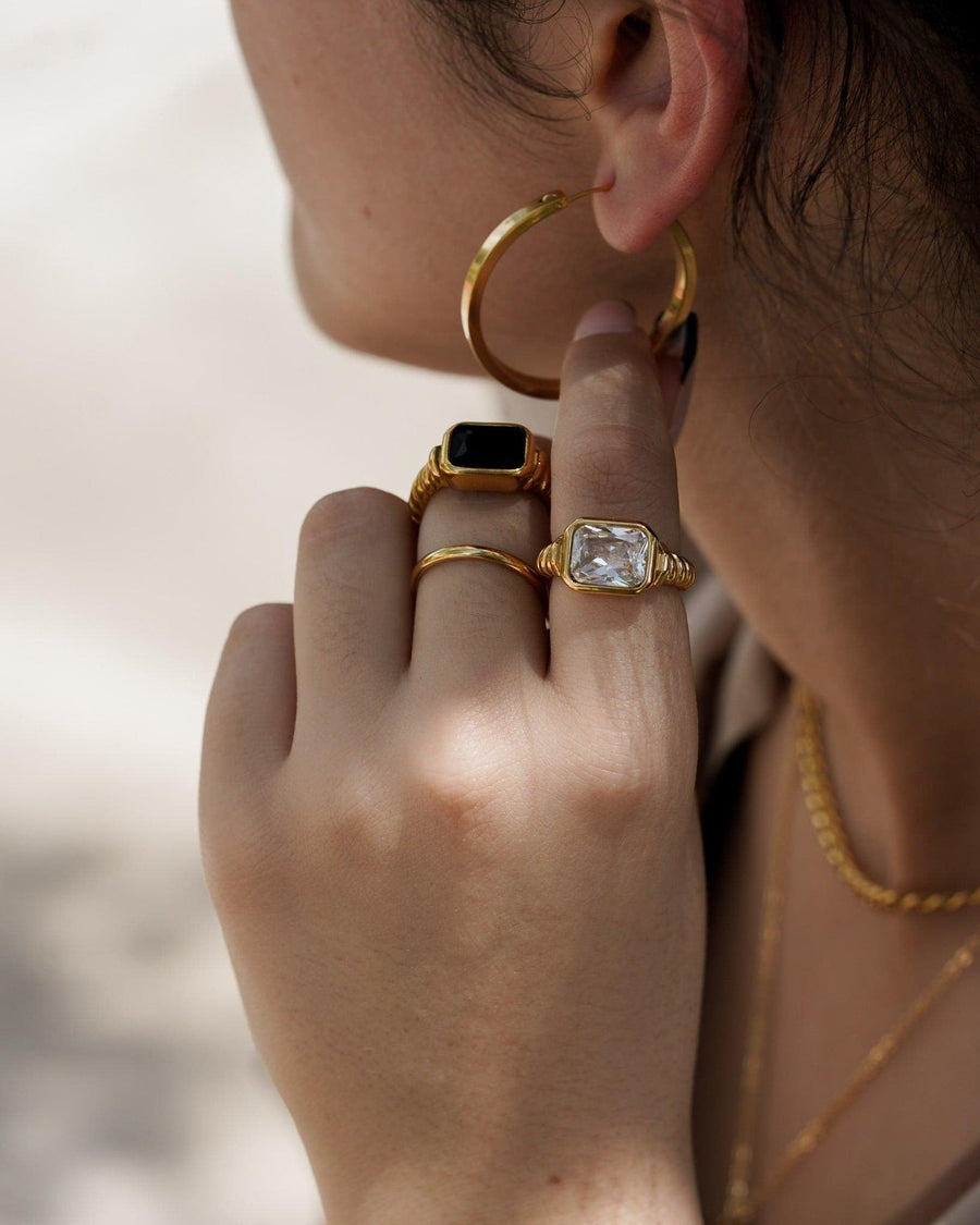 Style Image - Twisted Signet Ring in black worn with stacked gold rings and hoop earrings