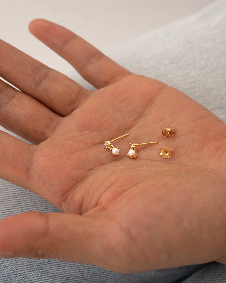Detail Image - Diamond pearl drop studs with posts and backs resting in an open palm