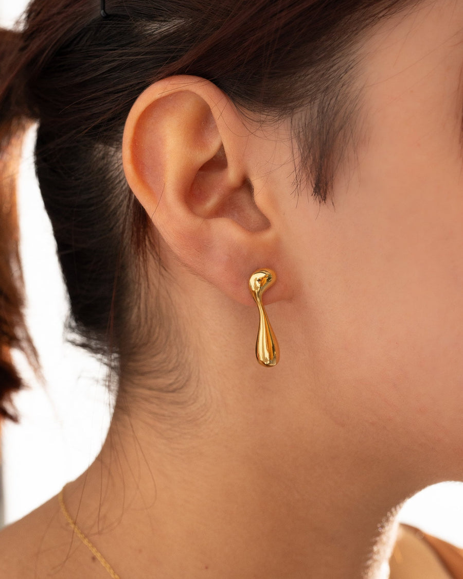 Style Image - Melted Gold Earrings worn on ear, showing the irregular drop stud shape in 14k gold plated stainless steel