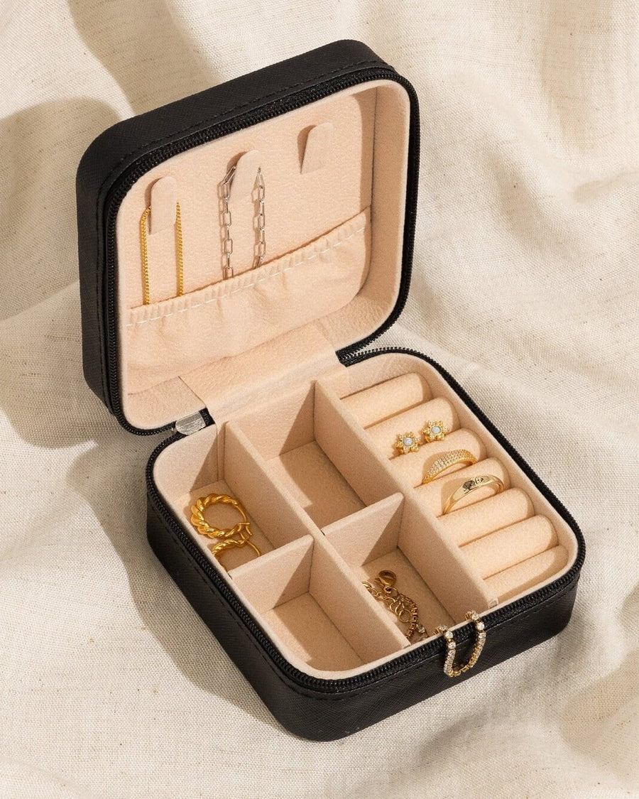 Model Image - Open black vegan leather jewelry travel case with zipper, compartments, ring slots, and assorted jewelry displayed inside worn on model