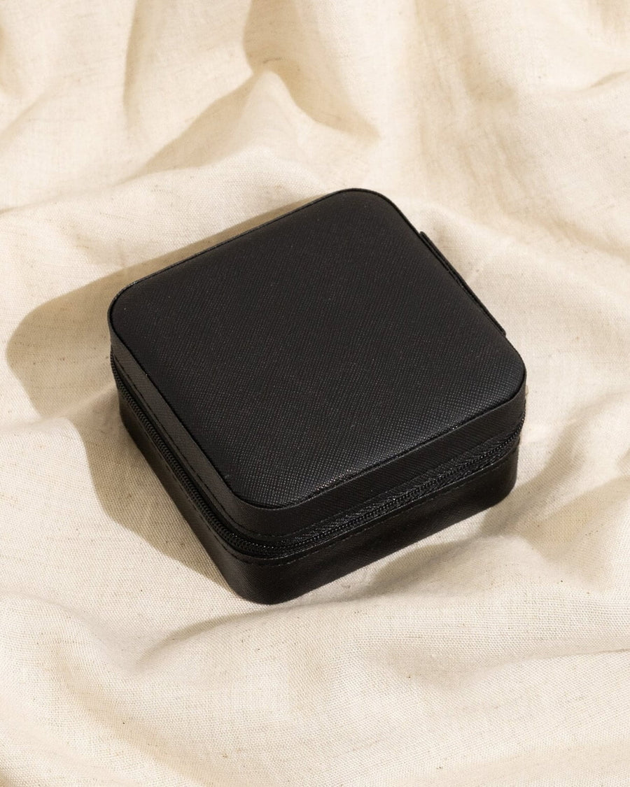 Detail Image - Closed black vegan leather jewelry travel case with zipper on fabric backdrop