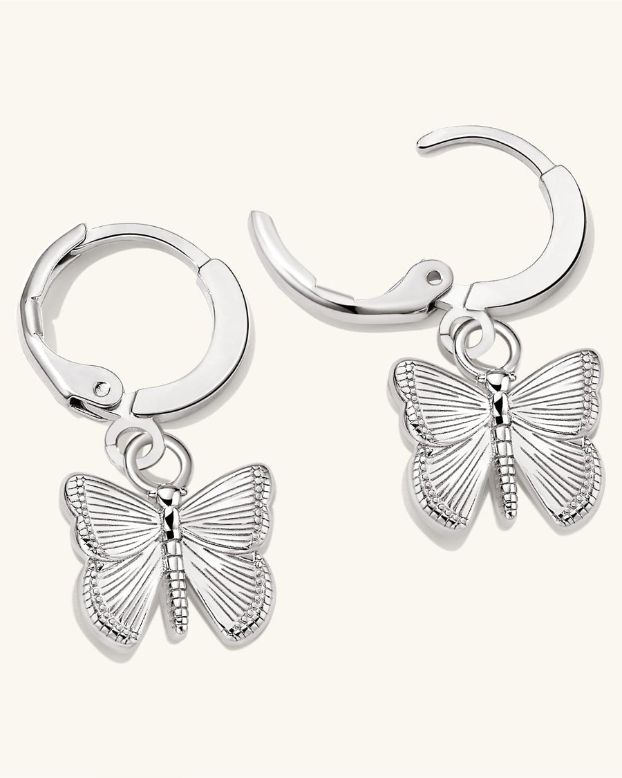 Detail Image - Silver finish on brass hoop earrings with dangling butterfly charms shown open against a light background