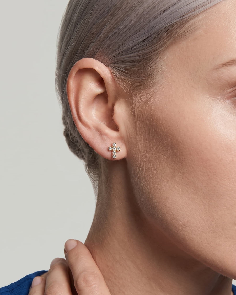 Model Image - tiny paved cross stud earring with sparkling accents on the earlobe worn on model