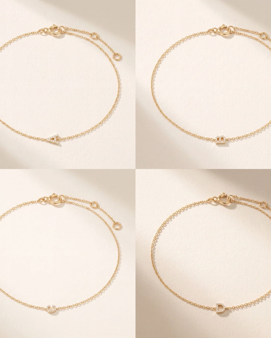 Style Image - Four 14k solid gold pave diamond initial bracelets with delicate chains and extender clasps arranged on a soft neutral background