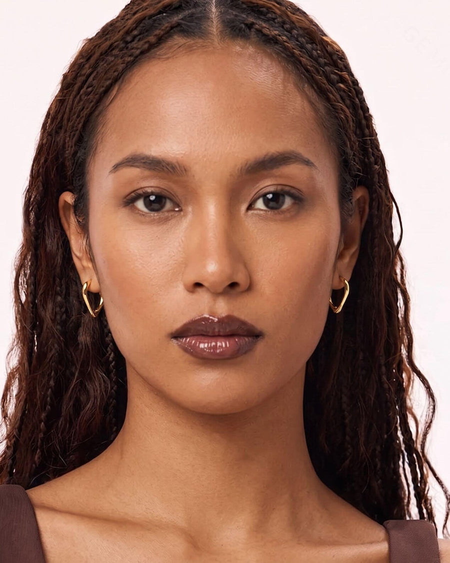 Style Image - Model wearing 14K gold heart hoop earrings with a sleek open silhouette.