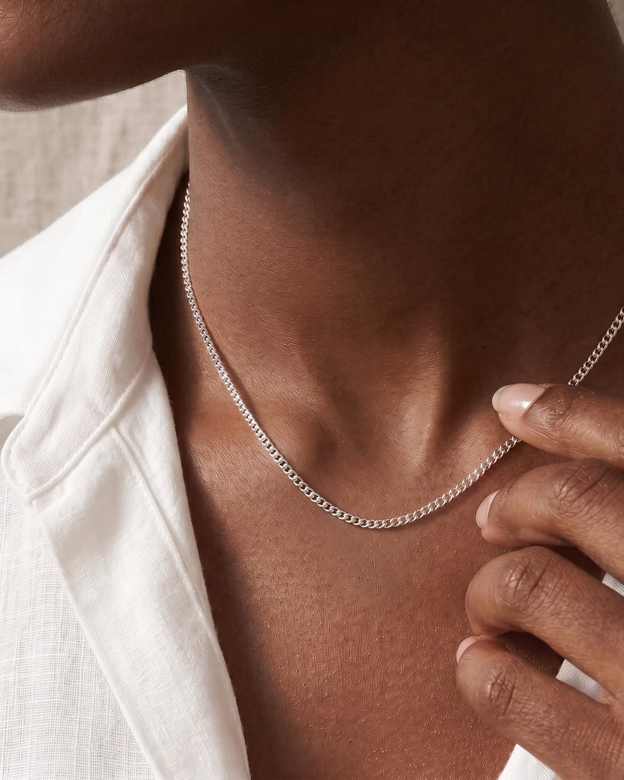 Model Image - Silver baby curb chain necklace resting at the neckline with a slim minimalist profile worn on model