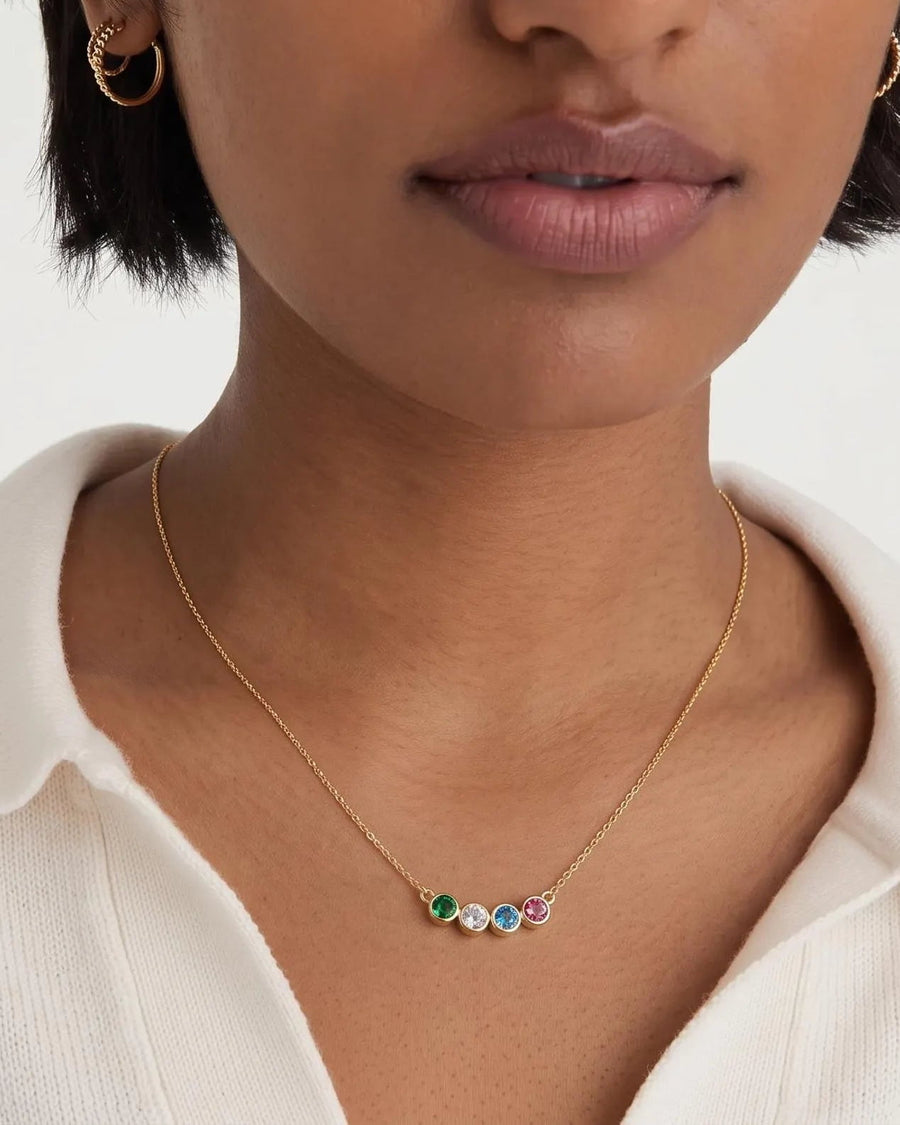 Model Image - A close-up of a model wearing a delicate gold chain necklace with three small colorful gemstone charms (green, blue, and purple) on a white collared shirt.