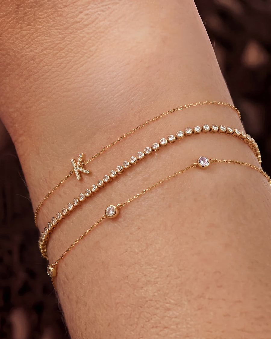 Style Image - Birthstone bezel bracelet layered on the wrist with delicate gold bracelets and small bezel-set gemstones.