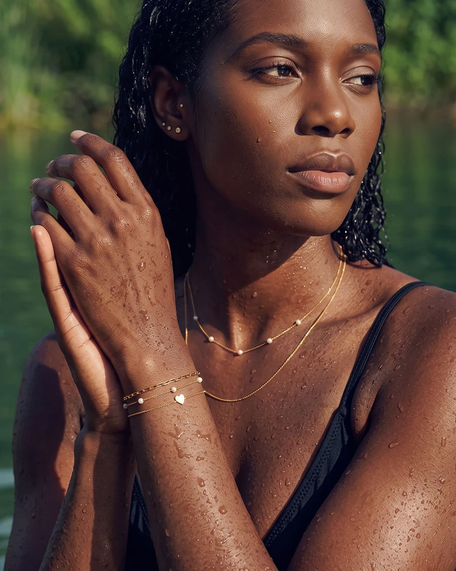 Style Image - Pearl station bracelet styled in a layered bracelet stack with delicate gold necklaces on a woman by the water.