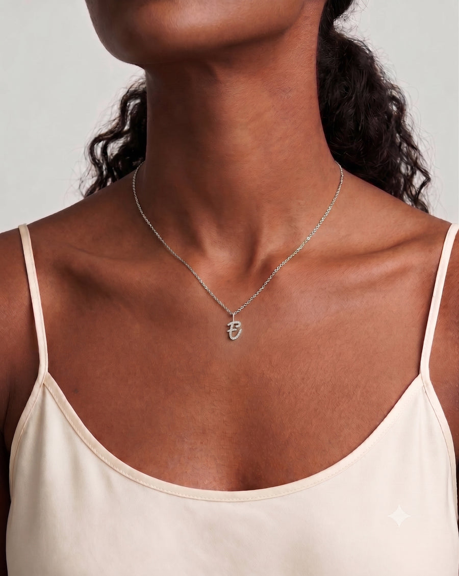 Model Image - A close-up of a model wearing a delicate silver chain necklace with a small initial pendant, styled with a cream camisole top against a light gray background.