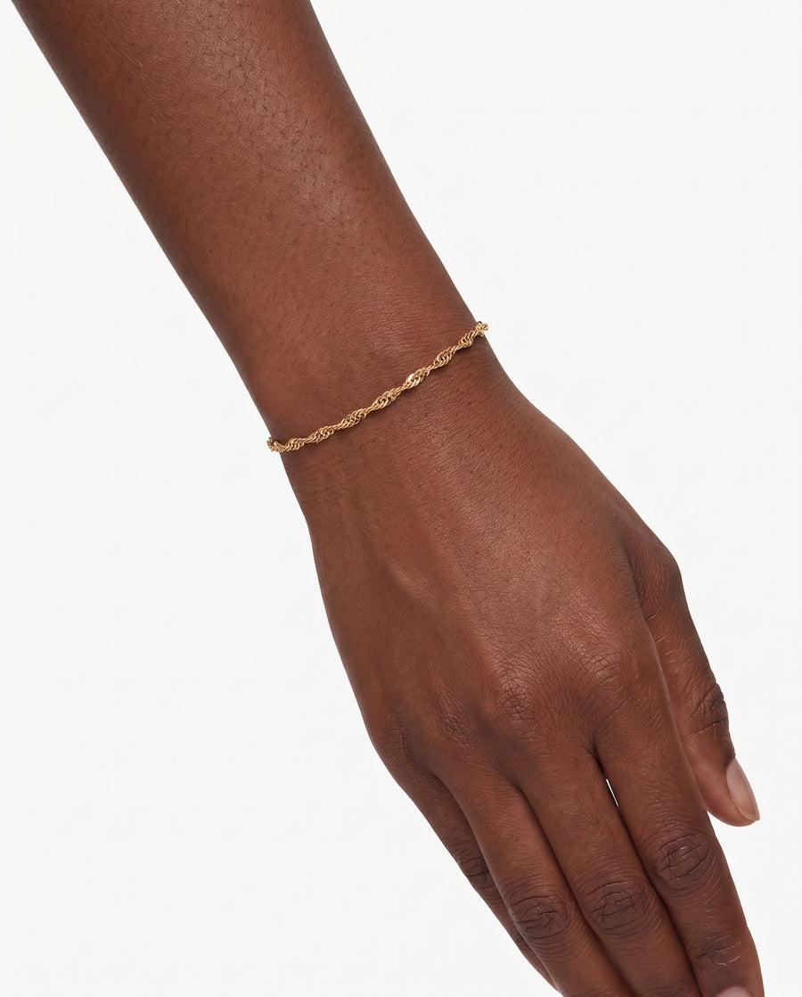 Model Image - A delicate gold chain bracelet with a twisted rope design, shown worn on a person's wrist against a clean white background.